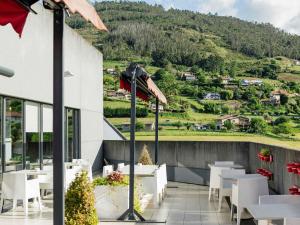a restaurant with white tables and chairs on a balcony at Ibis Oviedo in Oviedo