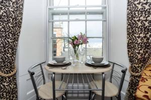 a table with chairs and a vase of flowers on a window at Union Street Apartment in Aberdeen