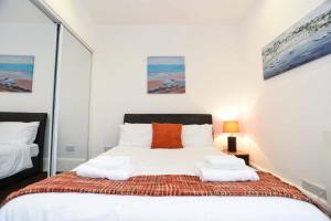 a bedroom with a bed with white sheets and orange pillows at Union Street Apartment in Aberdeen