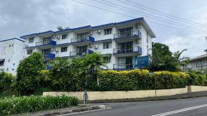 a large white building with blue trim on a street at Townhouse Apartment Hotel Suva in Suva