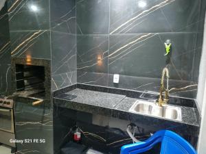 a bathroom with a sink and a black tiled wall at Barrinha Beach flats in Saquarema