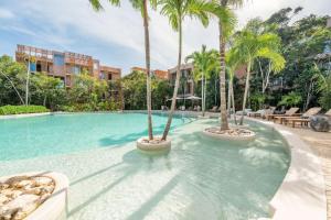 a swimming pool with palm trees in a resort at Amazing 1BR Tulum Jungle with Restaurant, Pool and Gym in Tulum