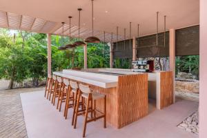 a kitchen with a counter with chairs around it at Amazing 1BR Tulum Jungle with Restaurant, Pool and Gym in Tulum