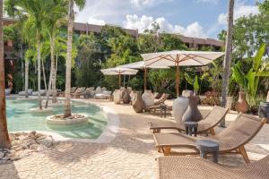a resort with a pool with chairs and umbrellas at Amazing 1BR Tulum Jungle with Restaurant, Pool and Gym in Tulum