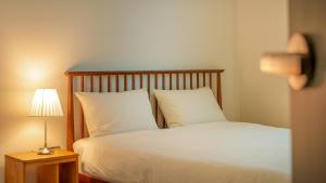a bed with white pillows and a table with a lamp at Sokcho Biroso Private Cottage in Sokcho