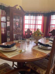 a wooden table with plates and utensils on it at The Cozy Haven Bed and Breakfast in Montego Bay