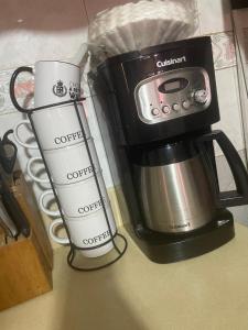 a coffee maker with a camera and two cups on a counter at The Cozy Haven Bed and Breakfast in Montego Bay