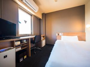 a hotel room with a bed and a television at Super Hotel Inn Kurashiki Mizushima in Kurashiki