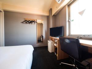 a hotel room with a bed and a desk and a tv at Super Hotel Inn Kurashiki Mizushima in Kurashiki