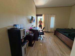 a man is standing in a room with a bedroom at Mamat warung bed & breakfast in Huu