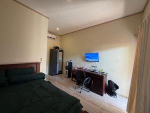 a bedroom with a bed and a desk with a computer at Mamat warung bed & breakfast in Huu
