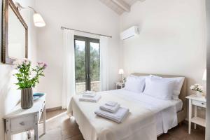 a white bedroom with a white bed and a window at Villa Ares in Bogdanátika +9 photos