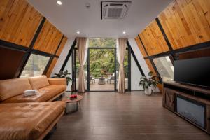 a living room with a couch and a tv at Cát Bà Sena Valley Retreat in Xuan Dam