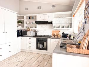 a kitchen with white cabinets and a stove top oven at Normandie On Sea in Hermanus