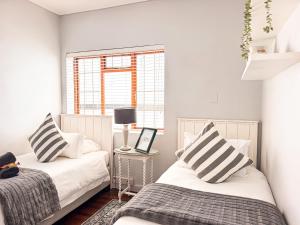 a bedroom with two beds and a window at Normandie On Sea in Hermanus