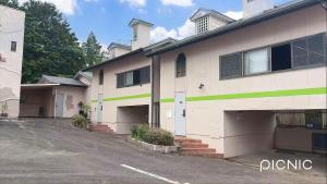 a white building with a green stripe on it at ホテルＪoＪo in Ikaho