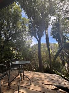 a table and chairs on a deck with palm trees at Mapua Cabbage Trees in Mapua