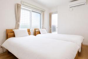 two beds in a bedroom with a window at BALOH Wadamisaki in Kobe