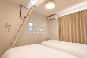 two beds in a room with a wall with a ladder at BALOH Wadamisaki in Kobe