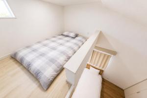 a white bedroom with a bed and a chair at BALOH Wadamisaki in Kobe