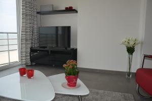 a living room with a white table and a tv at 4B @ Longchamp in Ostend