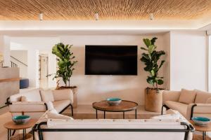 a living room with couches and a flat screen tv at MiM Mallorca member of Meliá Collection in Sa Coma