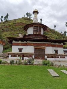 a large building with a hill in the background at Drukyul Kora Tours & Treks in Thimphu