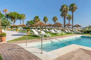 a pool with lounge chairs and umbrellas at a resort at Meliá Isla Canela in Isla Canela