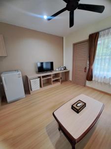 a living room with a ceiling fan and a table at Happy Cottage in Chalong