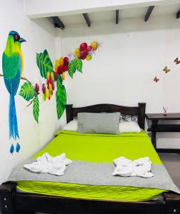 a bedroom with a green bed with a bird on the wall at hostal combi in Salento