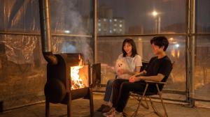 a man and a woman sitting in chairs next to a fire at Daebudo Banditbul Pension in Ansan