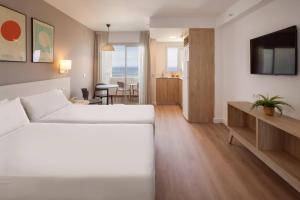 a bedroom with a white bed and a living room at SOL by Meliá Puerto Marina in Torremolinos
