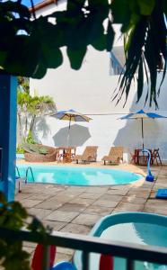 a swimming pool with two umbrellas and chairs and a table and chairsuggest at Capitolio 02 in Canoa Quebrada