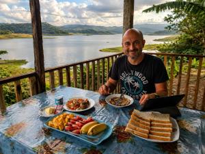 a man sitting at a table with plates of food at Elee Villa - Waterfront Retreat with Victoria Reservoir & Mountain Views in Teldeniya