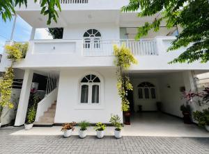 a white house with potted plants in front of it at Krautergarten Resort & Wellness in Negombo