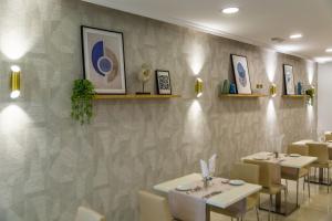 a dining room with white tables and chairs against a wall at Hotel Las Arenas, Affiliated by Meliá in Benalmádena