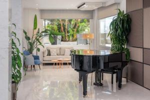 a black piano in a living room with plants at Hotel Las Arenas, Affiliated by Meliá in Benalmádena