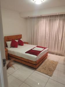 a bedroom with a large bed with red pillows at Pleasant Field Bed And Breakfast in Gaborone