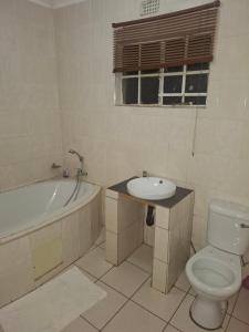 a bathroom with a toilet and a tub and a sink at Pleasant Field Bed And Breakfast in Gaborone