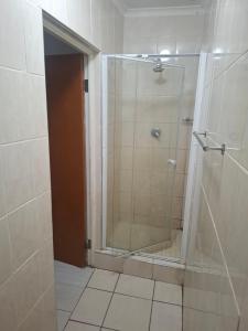 a shower with a glass door in a bathroom at Pleasant Field Bed And Breakfast in Gaborone