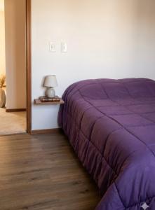 a purple bed in a room with a lamp on a table at Avellaneda in Mendoza
