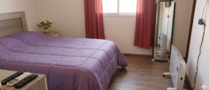 a bedroom with a purple bed and a desk with a computer at Avellaneda in Mendoza