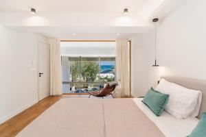 a bedroom with a bed and a chair and a window at NOMIA Seaside Living in Agios Nikolaos +87 photos
