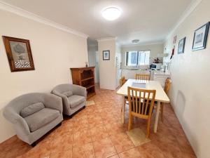 a living room with a table and chairs and a kitchen at Pacific Court 2 in South West Rocks