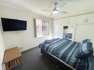a bedroom with a bed and a flat screen tv at Pacific Court 2 in South West Rocks