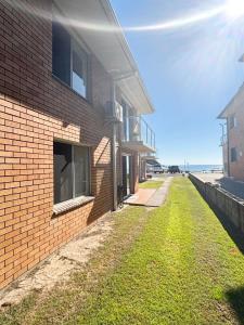a brick building with a grass yard next to the beach at Pacific Court 2 in South West Rocks