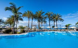 a large swimming pool with palm trees and umbrellas at Meliá Jardines del Teide - Adults Only in Adeje