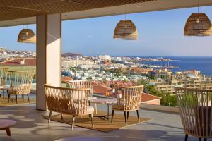 a patio with chairs and tables and a view of the city at Meliá Jardines del Teide - Adults Only in Adeje +78 photos
