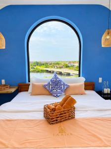 a bed with a basket on it with a window at La Riva Riverside Hue Hotel & Rooftop in Hue