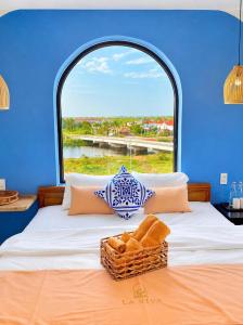 a bed with a window with a basket on it at La Riva Riverside Hue Hotel & Rooftop in Hue